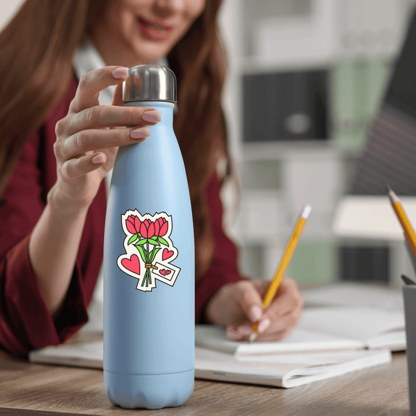 UV DTF transfer sticker with red flowers and hearts on blue water bottle at desk